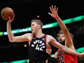 Jakob Poeltl of the Toronto Raptors leaps to pass over Denzel Valentine and Robin Lopez of the Chicago Bulls at the United Center on January 3, 2018 in Chicago, Illinois.