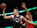 Jakob Poeltl of the Toronto Raptors leaps to pass over Denzel Valentine and Robin Lopez of the Chicago Bulls at the United Center on January 3, 2018 in Chicago, Illinois.  