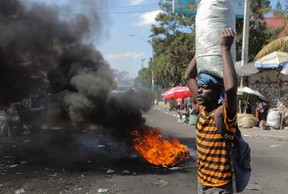 A merchant walks near a burning barricade as demonstrators hold a protest demanding justice for police officers killed by armed gangs, in Port-au-Prince, Haiti, Jan. 27, 2023.