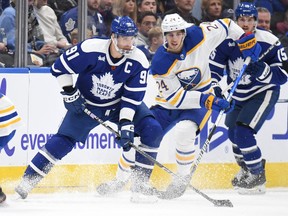 Nov 19, 2022; Toronto, Ontario, CAN;   Toronto Maple Leafs forward John Tavares (91) moves the puck away from Buffalo Sabes forward Dylan Cozens (24) in the third period at Scotiabank Arena.