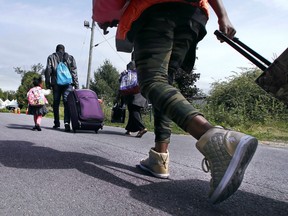 Migrants make the trek across the border in Quebec walking down Roxham Road in Champlain, N.Y., on Aug. 7, 2017.  (AP Photo/Charles Krupa)