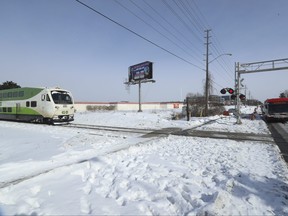 A southbound GO train heads across the flat crossing on Finch Ave. E. east of Kennedy Rd. as a TTC training bus sits at the crossing behind the barriers on Friday, Feb. 3, 2023. On Thursday night a TTC bus driver rescued people in a car who had mistakenly turned onto the northbound side of the tracks.