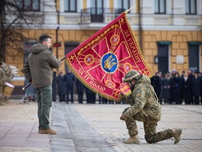 Ukraine's President Volodymyr Zelenskyy handovers a flag to a serviceman during a ceremony dedicated to the first anniversary of the Russian invasion of Ukraine, amid Russia's attack on Ukraine, in Kyiv, Feb. 24, 2023.