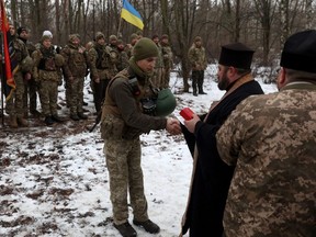 A Ukrainian Orthodox military priest awards artillerymen of the unit of the 14th Prince Roman the Great's Separate Mechanized Brigade as he visits them to maintain their morale near the front line in Kharkiv region, Saturday, Feb. 25, 2023, amid the Russian invasion of Ukraine.