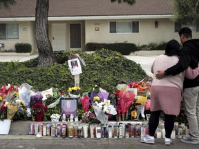 Maryann Torres, left, with her son Mason of San Dimas pray for Bishop David O'Connell next to a makeshift memorial, Tuesday, Feb. 21, 2023, in front of the Bishop's home in Hacienda Heights, Calif.
