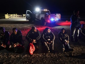 Migrants wait to be processed after crossing the border on Jan. 6, 2023, near Yuma, Ariz.
