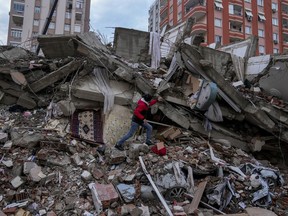 A man walks among rubble as he searches for people in a destroyed building in Adana, Turkey, Monday, Feb. 6, 2023.