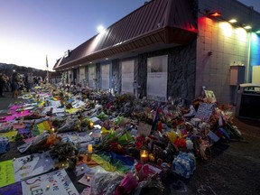 Mourners gather outside Club Q to visit a memorial, which has been moved from a sidewalk outside of police tape that was surrounding the club, Nov. 25, 2022, in Colorado Spring, Colo.