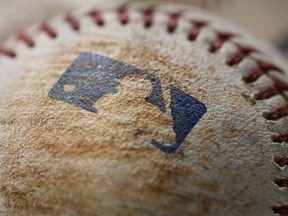 A close-up view of the stitches and leather surface of a baseball with the MLB logo on it is displayed prior to the start of batting practice before the Toronto Blue Jays MLB game against the Chicago White Sox on April 18, 2013 at Rogers Centre in Toronto, Ontario, Canada.