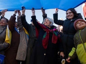 Governor General Mary Simon and Yuliya Kovaliv, Ambassador of Ukraine to Canada, right, hold a section of the Ukrainian flag during the 'Stand in Solidarity with Ukraine' event marking the one-year anniversary of the Russian invasion of Ukraine at the Flora Footbridge in Ottawa, Feb. 20, 2023.