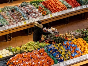A person pushes a shopping cart through the produce section of a grocery store in Toronto, Nov. 22, 2022.