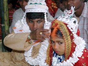 An Indian groom puts vermilion, the holy mark belived the as sign of Hindu marriage, on the forehead of his underage bride during a mass marriage programme in the village of Malda, March 2, 2006.