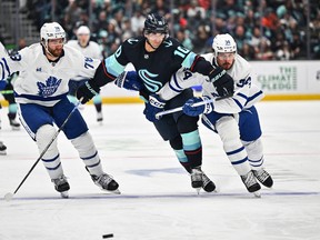 Maple Leafs' TJ Brodie (left) and Kraken's Matty Beniers and Maple Leafs' Auston Matthews (right) chase the puck during the second period at Climate Pledge Arena on Sunday, Feb. 26, 2023.
