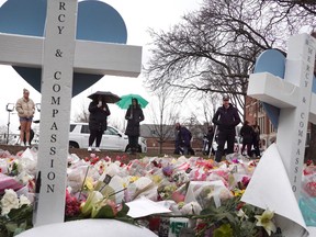 Flowers and crosses are set at the base of "The Rock" statue on the campus of Michigan State University as a tribute to the students killed and wounded in Monday's shooting on Feb. 16, 2023 in East Lansing, Michigan.
