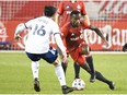 Toronto FC defender Richie Laryea dribbles the ball toward DC United forward Adrien Perez.
