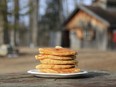 Closeup of stack of pancakes with log cabin in background.
