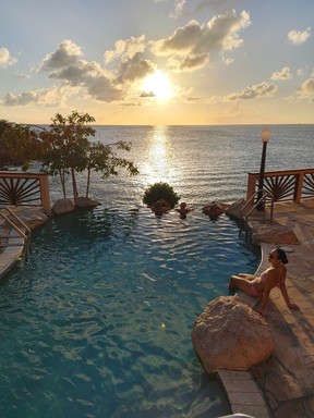 Tourists wait for the sun to set while cooling off at the Divi Little Bay Beach Resort’s infinity pool.