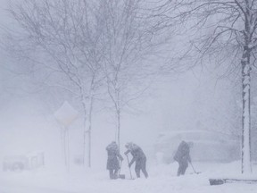 People shovel their driveways in a snow blizzard in Mississauga, Ont., on Wednesday, January 25, 2023.
