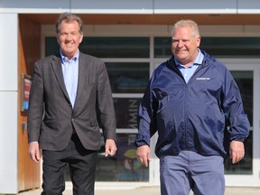 Doug Ford, right, walks with George Pirie  in front of the Timmins Museum on May 7, 2022.