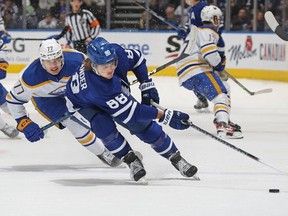 William Nylander of the Toronto Maple Leafs grabs a puck against JJ Peterka of the Buffalo Sabres  at Scotiabank Arena on March 13, 2023 in Toronto, Ontario, Canada.