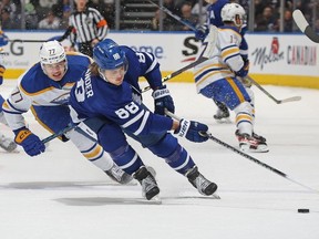 William Nylander of the Toronto Maple Leafs grabs a puck against JJ Peterka of the Buffalo Sabres at Scotiabank Arena on March 13, 2023 in Toronto, Ontario, Canada.