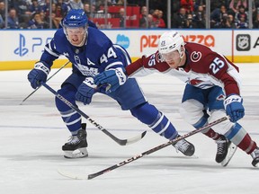 Morgan Rielly #44 of the Toronto Maple Leafs battles against Logan O'Connor #25 of the Colorado Avalanche for the puck during an NHL game at Scotiabank Arena on March 15, 2023 in Toronto. The Avalanche defeated the Maple Leafs 2-1 in overtime shootout.