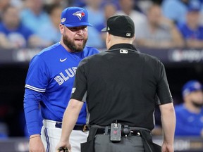 John Schneider #14 of the Toronto Blue Jays talks with umpire Todd Tichenor against the Seattle Mariners during the fifth inning in game two of the American League Wild Card Series at Rogers Centre on October 08, 2022 in Toronto.