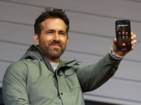 Ryan Reynolds speaks to Rob McElhenney, fellow co-owner of Wrexham, on the phone during the Emirates FA Cup Fourth Round match between Wrexham and Sheffield United at Racecourse Ground on January 29, 2023 in Wrexham, Wales.