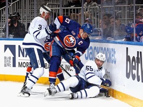 Justin Holl and Mark Giordano of the Toronto Maple Leafs defend against Anders Lee of the New York Islanders during the second period at the UBS Arena on March 21, 2023 in Elmont, New York.