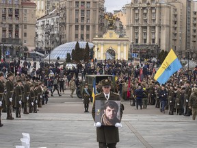 A serviceman carry a photo of Ukrainian officer Dmytro Kotsiubaylo, code-named "Da Vinci," during a commemoration ceremony in Independence Square in Kyiv, Ukraine, Friday, March 10, 2023.