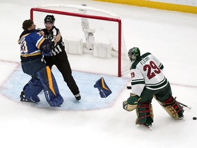 St. Louis Blues goaltender Jordan Binnington, left, is held back from fighting Minnesota Wild goaltender Marc-Andre Fleury (29) by linesman David Brisebois during the second period of an NHL hockey game Wednesday, March 15, 2023, in St. Louis. (AP Photo/Jeff Roberson)