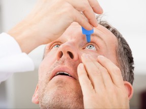 Close-up of a man putting eyedrops in his eyes.