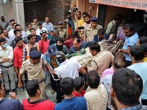 Rescue and security personnel carry a devotee on a stretcher who was injured after the floor covering a stepwell collapsed at a temple in Indore on March 30, 2023.