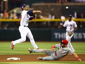 Mar 13, 2023; Phoenix, Arizona, USA; USA third baseman Nolan Arenado (left) throws to first base to complete the double play after forcing out sliding Canada base runner Edouard Julien in the sixth inning during the World Baseball Classic at Chase Field.
