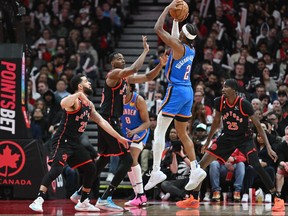 Oklahoma City Thunder's Shai Gilgeous-Alexander shoots the ball over Raptors' Christian Koloko and Fred VanVleet in the second half at Scotiabank Arena on March 16, 2023.