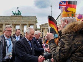 King Charles III and German President Frank-Walter Steinmeier greet well wishers following a ceremonial welcome at Brandenburg Gate in Berlin on March 29, 2023.