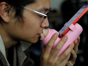 Jing Zhiyuan uses a remote kissing device "Long Lost Touch," as he demonstrates for camera how to use it during an interview with Reuters, at his home in Beijing, China, March 12, 2023.