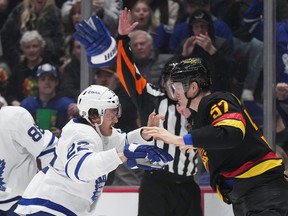 Maple Leafs' Jake McCabe (22) throws off his gloves as he fights Vancouver Canucks' Tyler Myers  during the first period of an NHL hockey game in Vancouver, on Saturday, March 4, 2023.
