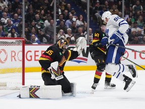 Toronto Maple Leafs' Ryan O'Reilly (90) is struck by the puck in front of Vancouver Canucks goalie Thatcher Demko (35) as Quinn Hughes (43) watches during the second period of an NHL hockey game in Vancouver, on Saturday, March 4, 2023.