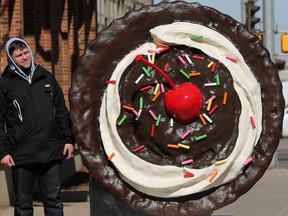 A pedestrians stops to check out a giant cookie along 104 street South of 104 Avenue in Edmonton on March 22, 2023. While there is no signage on the cookie a QR code does direct visitors to Crumbl Cookies Canada.