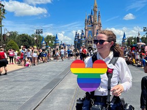 A Walt Disney World photographer holds a Pride rainbow-coloured Mickey Mouse cutout before the "Festival of Fantasy" parade at the Walt Disney World Magic Kingdom theme park in Orlando, Fla., July 30, 2022.