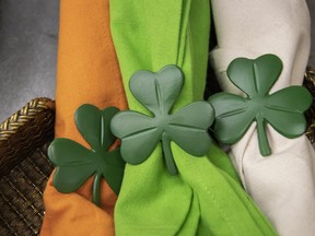 Closeup of Saint Patricks Day shamrock napkin holders on bright orange green and white cloth napkins in gold basket