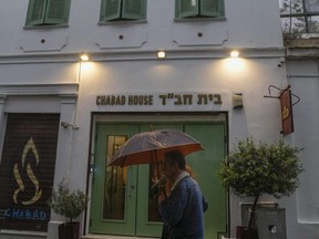 A man holding an umbrella walks past a Jewish restaurant that Greek officials believe was one of the targets of a planned terrorist attack, in Athens, Tuesday, March 28, 2023.