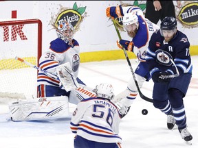 Winnipeg Jets centre Adam Lowry (17) and Edmonton Oilers defenceman Mattias Ekholm (14) eye a bouncing puck in front of Edmonton Oilers goaltender Jack Campbell (36) in the third period at Canada Life Centre in Winnipeg, March 4, 2023.