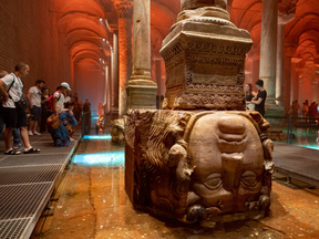 People stand next to the Medusa head in the Basilica Cistern while visiting the historic site in Istanbul, Turkey, July 26, 2022.