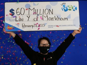 Woman holding giant $60-million Lotto max cheque over her head.