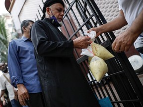 A muslim man receives two bags of porridge from a mosque committee to break his fast on the first day of Ramadan at a mosque in Kuala Lumpur, Malaysia March 23, 2023.