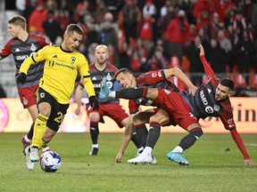 Columbus Crew midfielder Alexandru Matan (left) controls the ball as Toronto FC defender Raoul Petretta (28) collides with a teammate in the first half at BMO Field last night.