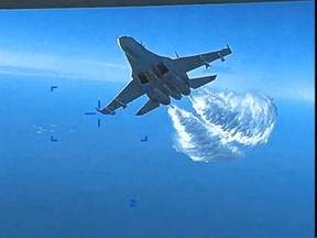 A Russian Su-27 aircraft dumps fuel while flying upon a  U.S. Air Force intelligence, surveillance, and reconnaissance unmanned MQ-9 aircraft over the Black Sea, March 14, 2023 in this still image taken from a handout video.