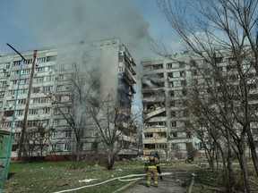 Rescuers stand in front of a residential building damaged by a Russian missile strike, amid RUssia's attack on Ukraine, in Zaporizhzhia, Ukraine March 22, 2023.